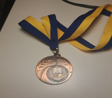A medal with a blue and yellow ribbon

Description automatically generated