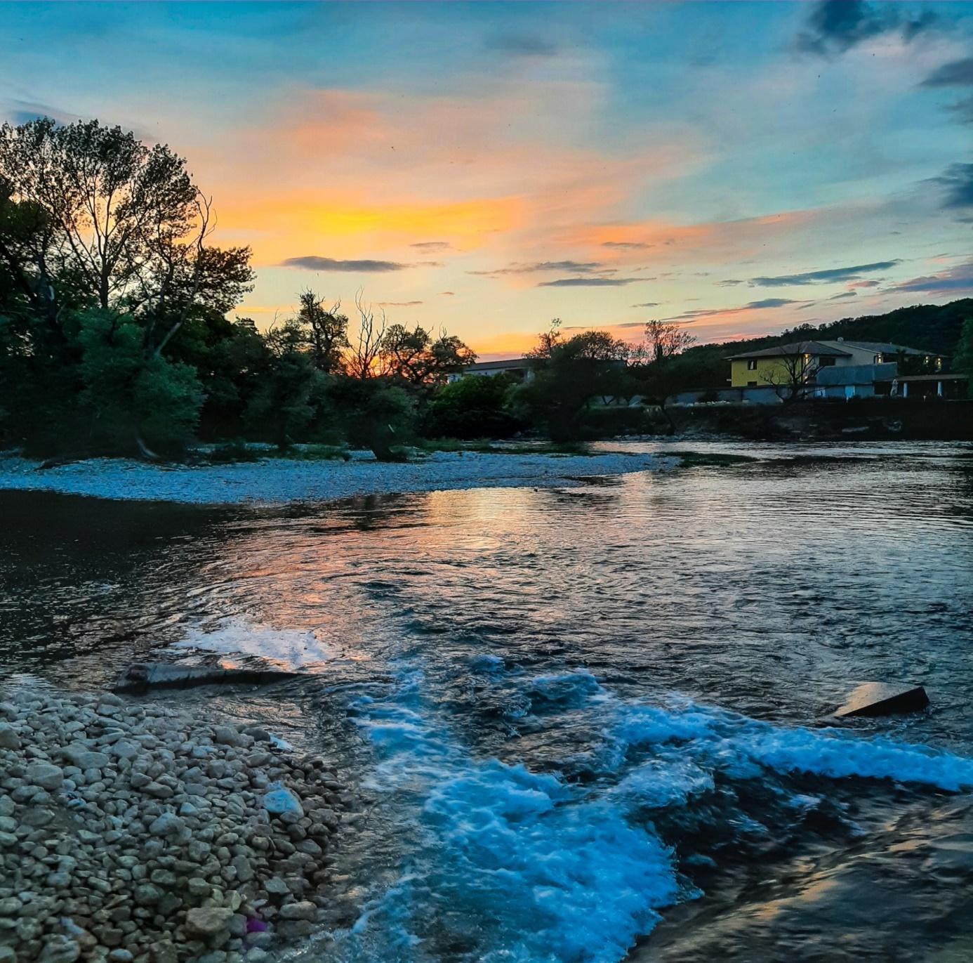 A river with rocks and trees in the background

Description automatically generated
