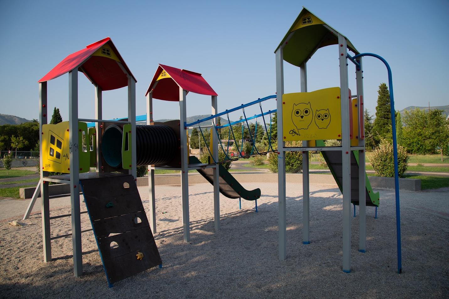 A playground with a slide and a bridge

Description automatically generated